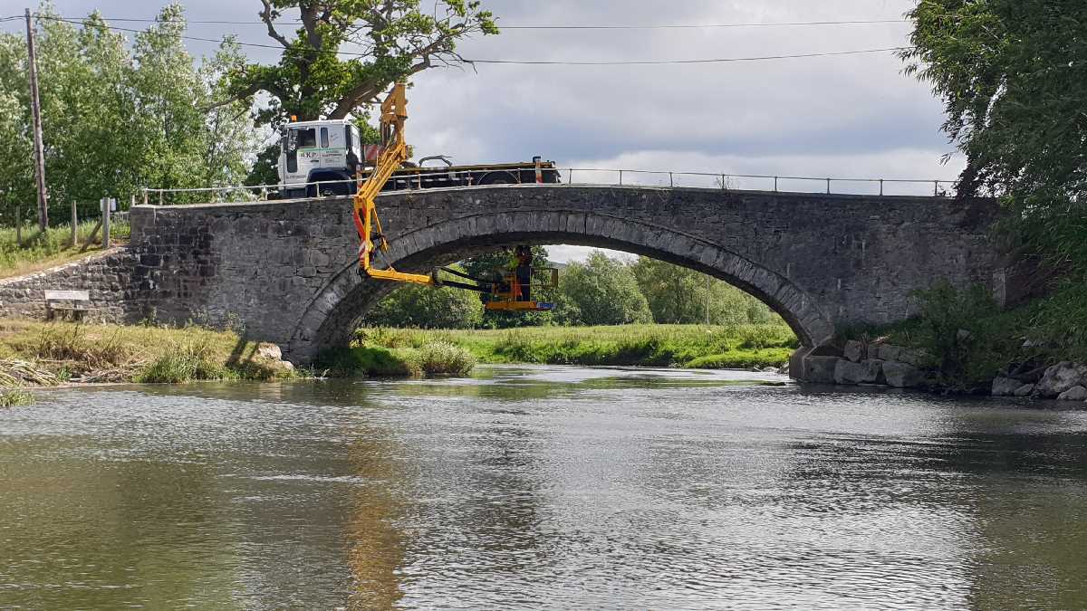 Llannerch Bridge - a stone masonry arch bridge, being inspected by a member of staff working from suspended cherry picker van